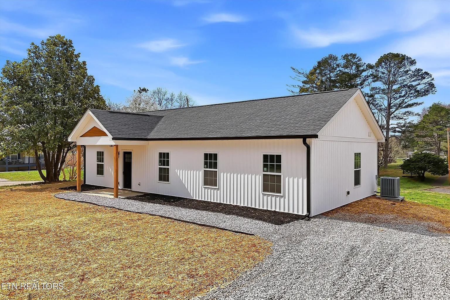 White board-and-batten farmhouse-style new construction home with dark roof and cedar accent columns